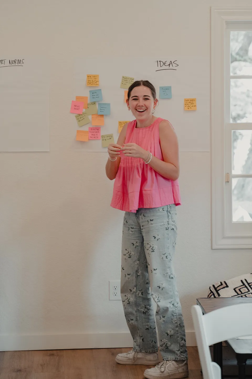 A LeapYear student smiling beside a wall of ideas during the retreat